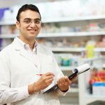 cheerful pharmacist chemist woman standing in pharmacy drugstore
